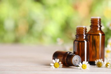 Beyaz ahşap masada, arka planda bulanık duran yağ ve papatya çiçekleri, yakın plan. Metin için boşluk