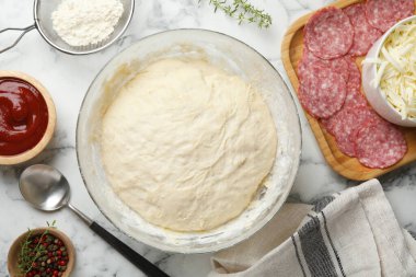 Calzone pizzası yapıyorum. Beyaz mermer sehpada farklı malzemeler var.