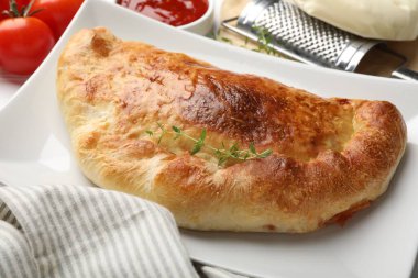 Lezzetli taze calzone pizza ve malzemeler masada, yakın plan.