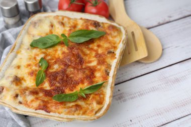 Hafif ahşap masada servis edilen fesleğenli nefis pişmiş lazanya, yakın plan. Metin için boşluk