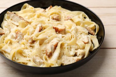 Hafif ahşap masada tavuklu lezzetli Alfredo makarnası, yakın plan.