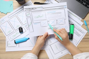 Kağıt üzerinde kablo çerçevesi oluşturan web sitesi tasarımcısı ahşap masa, üst görünüm kalem