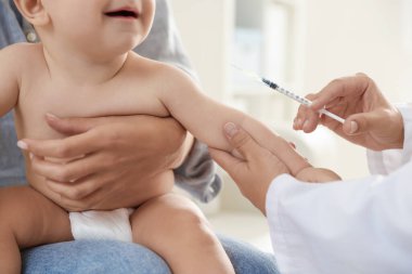 Pediyatrist klinikte bebek aşılıyor.