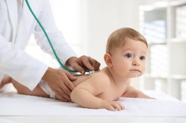 Pediyatrist, klinikte steteskoplu küçük bir çocuğu muayene ediyor. Bebeğin sağlığını kontrol ediyorum.