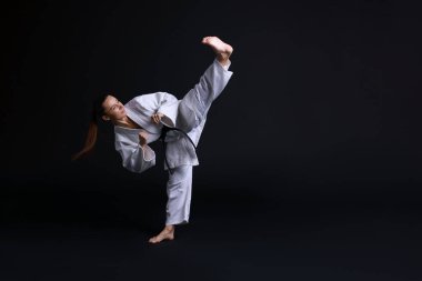 Kimonolu genç kadın siyah arka planda karate çalışıyor, mesaj için yer var.