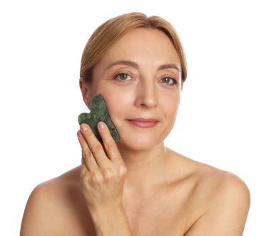 Beyaz arka planda gua sha aracıyla yüz masajı yapan güzel bir kadın.