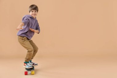 Bej arka planda kaykay yapan küçük bir çocuk, mesaj için yer var.