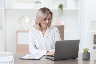 Ofiste dizüstü bilgisayarda çalışan iş kadını.