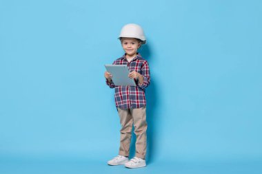 Açık mavi arka planda mimar gibi davranan tabletli küçük kız. Geleceğin mesleğini hayal etmek