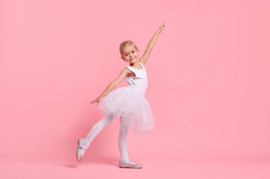 Pembe arka planda balerin gibi davranan küçük kız. Geleceğin mesleğini hayal etmek