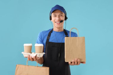 Kese kağıdı ve açık mavi arka planda fincanları olan fast-food işçisi.