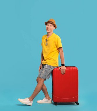 Açık mavi arka planda bavulu olan mutlu bir yolcu. Metin için boşluk