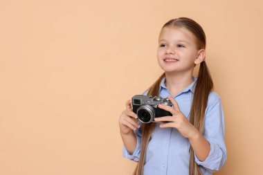 Bej arka planda fotoğrafçı gibi davranan kameralı küçük bir kız. Mesaj için yer var. Geleceğin mesleğini hayal etmek