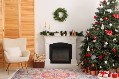 Odada şöminenin yanında süslenmiş Noel ağacı. Şenlikli iç tasarım