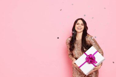 Hediye kutusu olan mutlu kadın ve pembe arka planda düşen konfeti, mesaj için yer. Sürpriz parti.