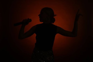 Karanlık arka planda şarkı söyleyen kadın silueti