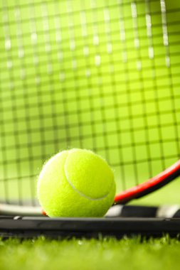 Tenis raketleri ve top yeşil suni çimlerde, yakın plan.