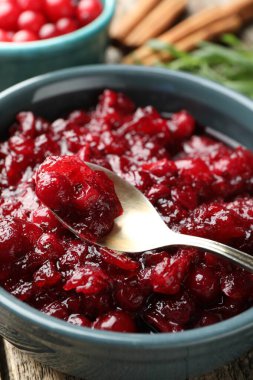 Lezzetli kızılcık sosu kasede ve kaşıkta masada, yakın plan.