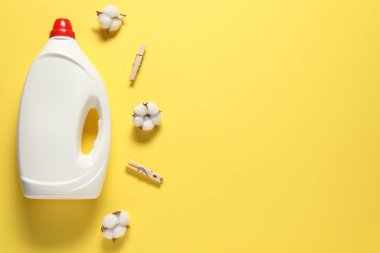 Çamaşır deterjanı, mandallar ve sarı arka planda pamuk çiçekleri olan bir şişe. Metin için boşluk