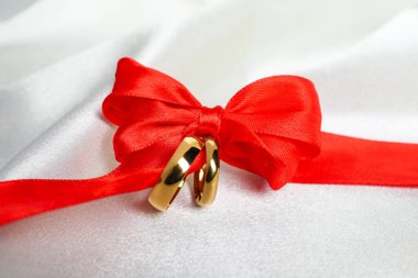 Alyanslar beyaz kumaş üzerine kurdeleyle bağlanmış, yakın plan.