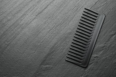 Gri arka planda bir plastik saç tarağı, üst manzara. Metin için boşluk