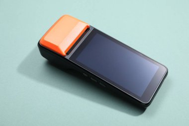 Soluk turkuaz arka planda bir ödeme terminali, yakın plan.