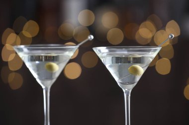Arka planda bulanık zeytinli martini kokteyli, yakın plan. Bokeh etkisi