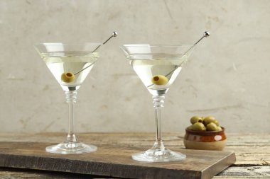 Ahşap masada zeytinli martini kokteyli.