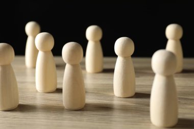 İnsan kaynakları konsepti. Masadaki birçok tahta figür koyu arkaplana karşı, yakın plan