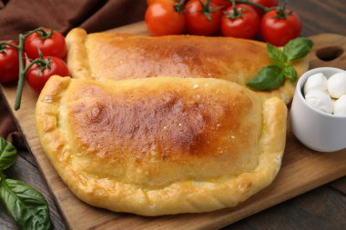 Lezzetli vejetaryen calzones fesleğen, mozarella peyniri ve domatesler ahşap masada, yakın plan.