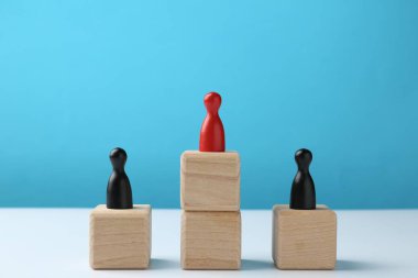 Tahta bloklardaki insan figürleri, açık mavi arka plandaki kırmızı figürler. Rekabet konsepti