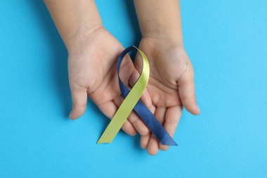 Arka planda sarı ve mavi kurdeleli çocuk, üst manzara. Down sendromu farkındalığı