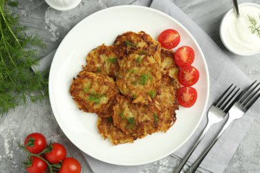 Delicious potato pancakes served on grey textured table, flat lay clipart