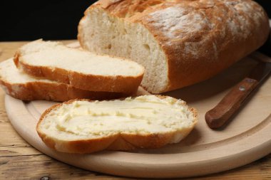 Tahta masada tereyağı ve bıçakla taze ekmek, yakın plan.