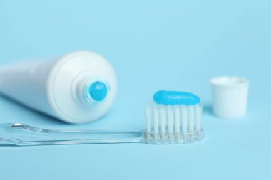 Diş fırçası ve açık mavi arkaplanda tüp, yakın plan.