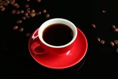 Kahveli kırmızı bardak ve siyah arkaplanda kızarmış fasulye.