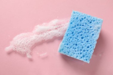 Pembe arka planda bir temizlik süngeri ve köpük.