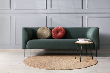 Rahat bir kanepe ve gri duvarın yanındaki yan masa.