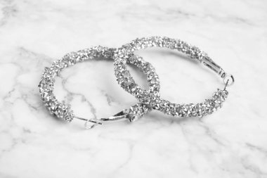 Güzel bijouterie. Beyaz mermer masadaki zarif küpeler, yakın plan.