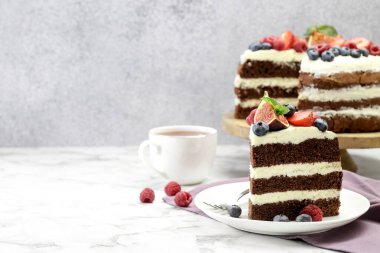 Beyaz masada servis edilen böğürtlenli bir parça çikolatalı kek. Metin için boşluk