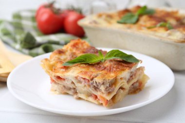 Lezzetli pişmiş lazanya. Fesleğenli beyaz masa, yakın plan.