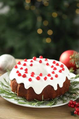 Geleneksel Noel pastası kırmızı frenk üzümü ve ahşap masada biberiye ile süslenmiş.