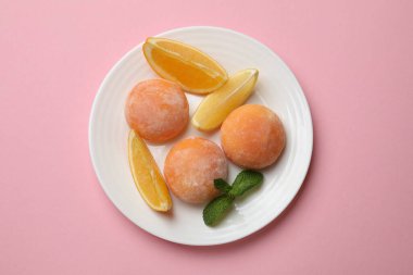 Lezzetli mochi tabağı, portakalı kes ve pembe masaya nane şekeri koy.