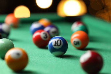 Birçok renkli bilardo topu yeşil masada, kapalı alanda, yakın planda.