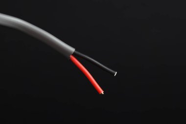 Siyah arka planda gri şeritli elektrik kablosu, yakın plan.