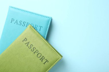 Açık mavi arkaplanda renkli pasaportlar, üst manzara. Metin için boşluk