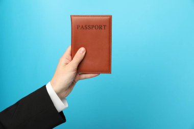 Açık mavi arka planda pasaportu olan bir kadın, yakın plan. Metin için boşluk