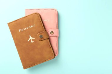 Turkuaz arka planda, parlak kapaklı iki pasaport, üst manzara. Metin için boşluk