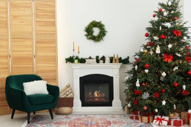 Odada şöminenin yanında süslenmiş Noel ağacı. Şenlikli iç tasarım