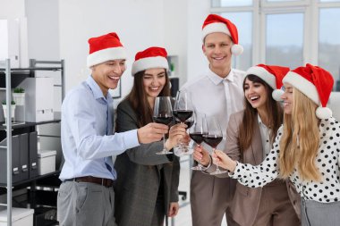 Mutlu iş arkadaşları ofis yılbaşı partisinde kadeh tokuşturuyor.